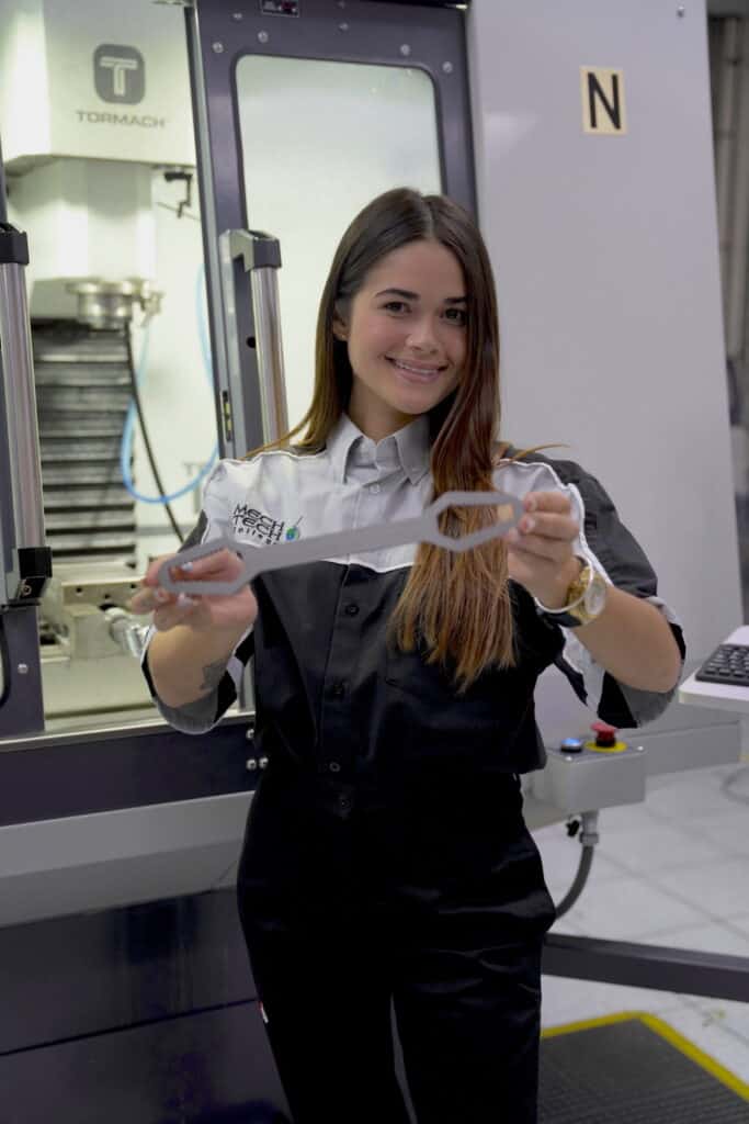 Estudiante de Tool & Die Maker con una pieza que hizo en el taller